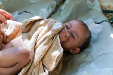 Annesiyle banyodan sonra kahverengi havluyla gezen Asyalı tatlı bir kızın portresi.