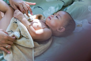 Annesiyle banyodan sonra kahverengi havluyla gezen Asyalı tatlı bir kızın portresi.