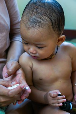 Bir anne, küçük tatlı Asyalı kızına vücut kremi sürer.