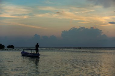 KEPULAUAN SERIBU - JAKARTA, 14 Nisan 2024 Sabahleyin geleneksel bir teknede kürek çeken bir adam.