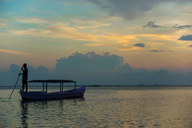KEPULAUAN SERIBU - JAKARTA, 14 Nisan 2024 Sabahleyin geleneksel bir teknede kürek çeken bir adam.