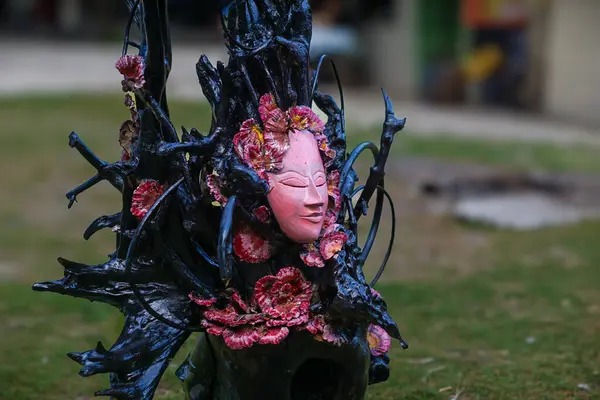 Geleneksel pembe Asya ahşap maskesi siyah bir ağaca bağlıdır..