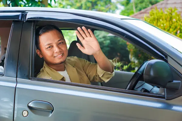 Arabadaki Asyalı bir adam elini pencereden dışarı salladı..