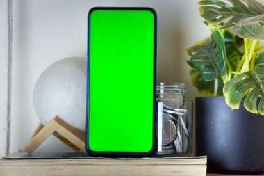 Portre pozisyonunda bir kitabın üzerine yeşil ekran yerleştirilmiş akıllı bir telefon.