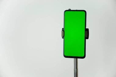 Bir telefon kulübesine yerleştirilmiş, portre pozisyonunda yeşil ekranlı ve beyaz arka planda izole edilmiş bir telefon. Boşluğu kopyala