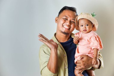 Sevimli bebeğini sevimli bir şapkanın içinde tutan mutlu bir baba. İkisi de sıcak bir şekilde gülümsüyor, sevgi dolu bir aile anı sergiliyorlar..