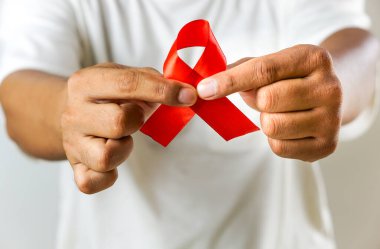 AlDS farkındalığını ve HIV 'in önlenmesine verilen desteği sembolize eden kırmızı kurdeleyi tutan bir el resmi, beyaz bir arkaplanda izole edilmiş..