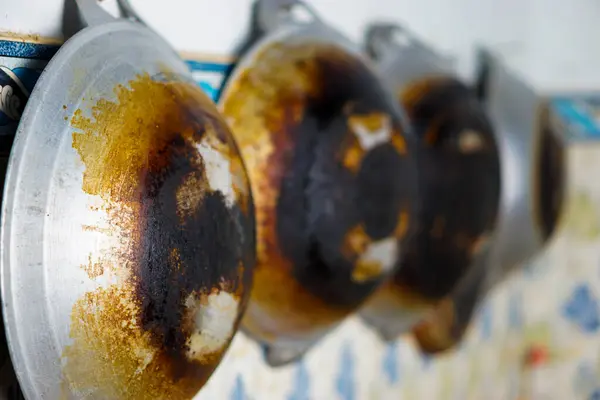 stock image A close-up of a charred and rusted frying pan hanging in the kitchen, showing heavy use and wear.