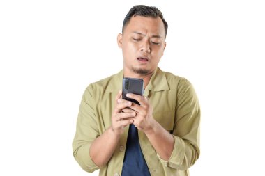 Bej ceketli bir adam akıllı telefonuna şaşkın bir ifadeyle bakar, muhtemelen teknik bir sorunla ilgilenir ya da beklenmedik haberler alır..