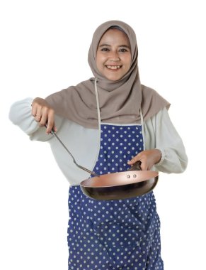 Başörtüsü ve önlük takan bir kadın akıllı bir telefon tutar, parmağını kaldırır, neşeli bir ifadeyle bir şeyi açıklar ya da gösterir gibi..