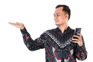 Geleneksel batik tişörtlü gülümseyen bir adam bir elinde akıllı bir telefon, diğerinde ise el kol hareketi yapar. Onun ifadesi güven ve coşku yayar. Endonezya Batik Günü