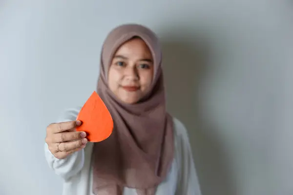 Kan Bağışı Günü 'nü temsil eden kırmızı su damlası sembolü tutan bir kadın beyaz bir zemine karşı..