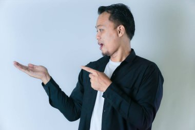 Siyah gömlekli bir adam avucunun içini gösterir. Beyaz arka planda bir şey ima eder ya da gösterir..