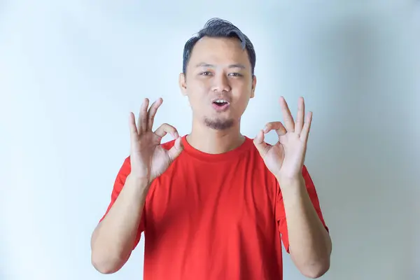 İki eli de kırmızı gömlekli bir adam gülümseyerek 