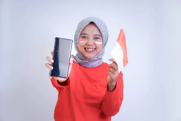 Endonezya Bağımsızlık Günü 'nü kutlamak için elinde akıllı bir telefonla elinde bayrak sallayan bir kadın..