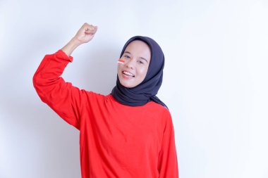 Endonezya 'nın 17 Ağustos' taki bağımsızlık gününü kutlamak için elini sıkan, başörtüsü takan genç bir Endonezyalı kadın, ışıl ışıl bir gülümsemeyle resmediliyor..