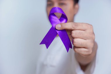 Elinde mor bir kurdele tutan bir kişi, farkındalığı ve kanser de dahil olmak üzere çeşitli nedenleri sembolize ediyor. Sağlık ve Dünya Kanser Günü konsepti
