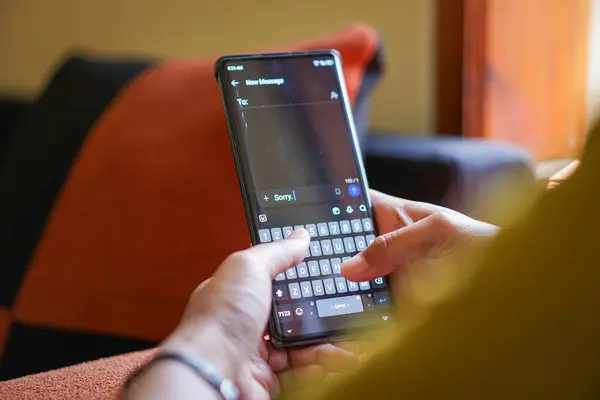 Akıllı telefondan özür mesajı yazan, rahat bir koltukta modern iletişimi sergileyen biri..