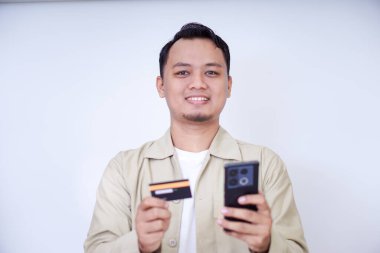 Akıllı telefon ve kredi kartı tutan neşeli bir adam alışverişe hazır..