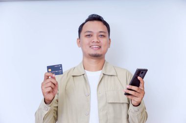 Akıllı telefon ve kredi kartı tutan neşeli bir adam alışverişe hazır..