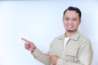 Bej ceketli gülümseyen bir adam elleriyle bir şeyi işaret eder..