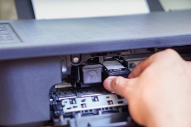 Bir kişi bir yazıcıya siyah mürekkep kartuşu yüklüyor..