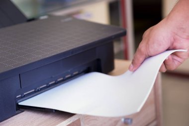 Bir yazıcıdan basılı kağıt alan kişi