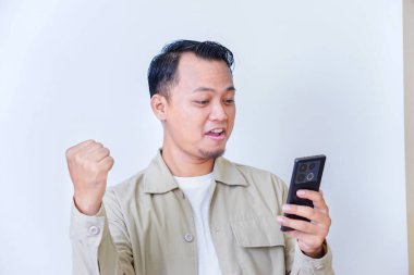 Bir adam akıllı telefonuyla heyecan verici bir şeye neşeyle tepki verir..