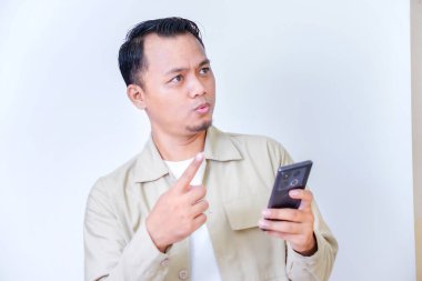 Elinde telefon tutan bir adam parmağını kaldırırken şaşırmış görünür..