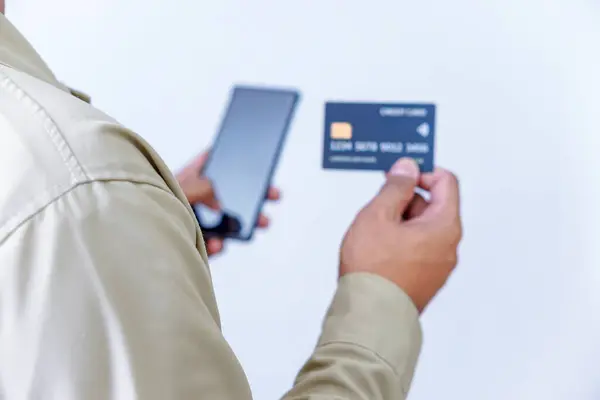 Kredi kartı ve telefon tutan bir kişi, işlem ya da ödeme için hazır..