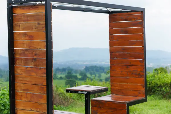 Ahşap panelleri olan rahat bir açık hava oturma alanı, doğanın manzarasını sunuyor..