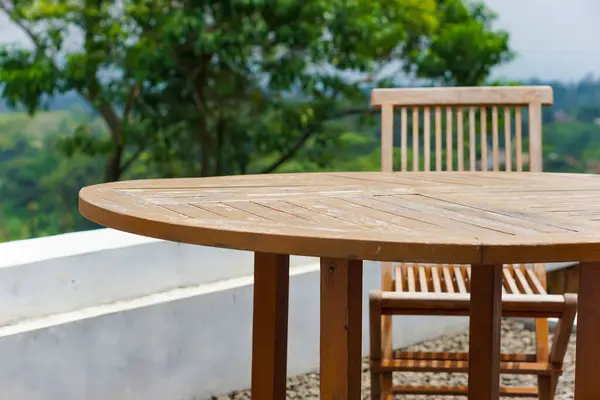 Bir ahşap yemek masası ve yeşil yapraklı sakin bir yere kurulmuş bir sandalye..