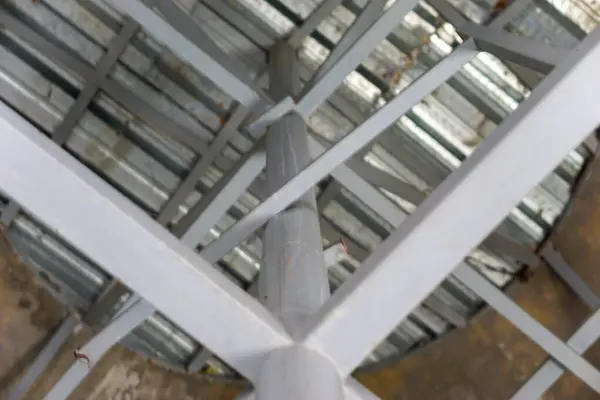 Aşağıdan çelik kirişlerin ve çatı yapısının yakın çekim görüntüsü, tasarım ve dokuyu gösteriyor.