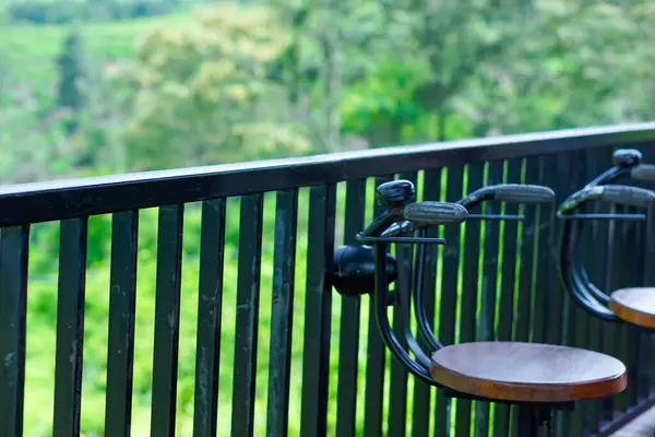 Şık sandalyeler ve yemyeşil manzaralı sakin bir balkon manzarası..