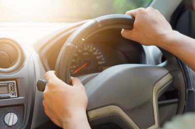 Bir arabanın direksiyonuna tutunan, direksiyona odaklanmış biri..