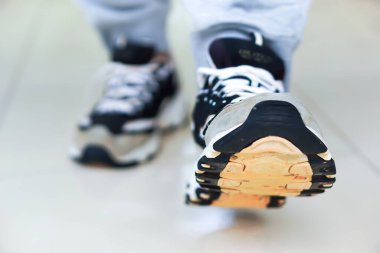 Bir spor ayakkabısının yakın çekimi pürüzsüz bir yüzeye doğru adım atar, hareket ve stili gösterir..