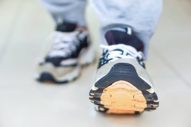 Bir spor ayakkabısının yakın çekimi pürüzsüz bir yüzeye doğru adım atar, hareket ve stili gösterir..