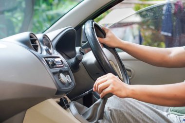 Sürücü, direksiyonu arabanın içinde tutarken vitesi ayarlar..