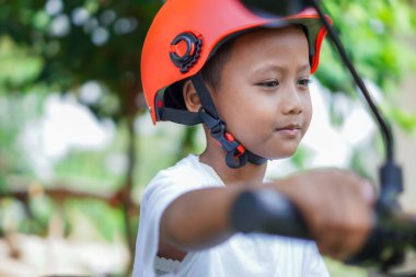 Parlak kasklı mutlu bir Asyalı çocuk elektrikli scooter 'da rahatça poz verir.