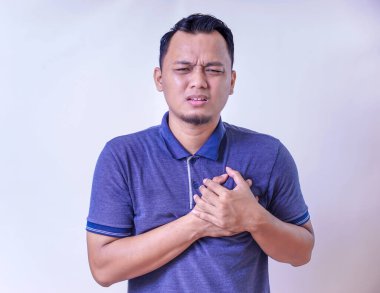 Asyalı bir adam göğüs rahatsızlığı yaşıyor gibi görünüyor. Acı ve endişe belirtileri gösteriyor..
