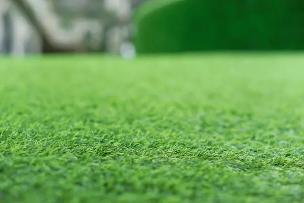 Pürüzsüz bir yüzeyi kaplayan yemyeşil yapay ot, peyzaj ve eğlence için ideal..