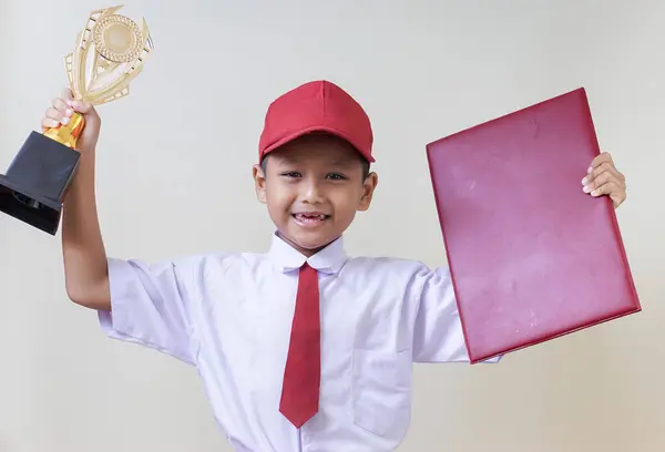 Bir ödül ve sertifikayla kutlama yapan neşeli bir Asyalı çocuk akademik başarı sergiliyor..