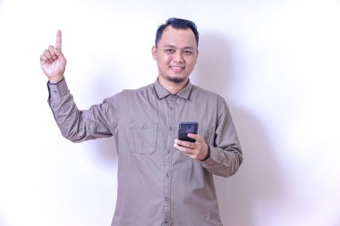 Asyalı bir adam akıllı telefonu tutarken ve elini uzatırken gülümser.