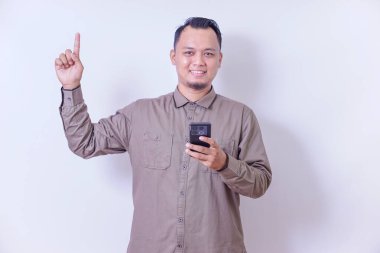 Asyalı bir adam akıllı telefonu tutarken ve elini uzatırken gülümser.