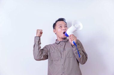 Asyalı bir adam megafona tutkuyla bağırıyor, heyecanını ve kararlılığını ifade ediyor..