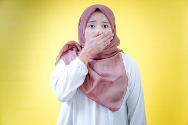 Başörtüsü takan Asyalı bir kadın şaşkınlık ya da şok gösterir, eliyle ağzını kapatır.