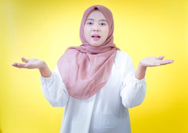 Parlak sarı bir zemin karşısında şaşırdığını ya da şaşırdığını ifade eden Asyalı bir kadın.