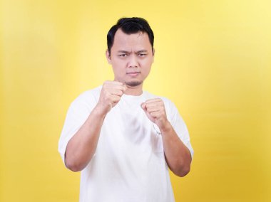 Kendine güvenen Asyalı bir adam parlak sarı bir arka plana karşı savaşmaya hazır.