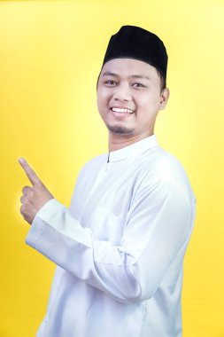 Asyalı Müslüman bir adam gülümsüyor ve yukarıya bakıyor.