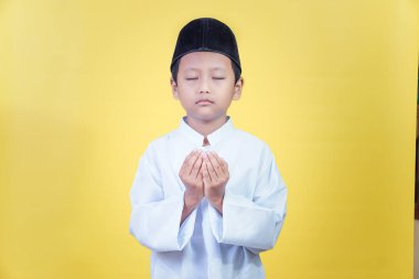 A young asian boy in prayer attire reflects the spirit of Ramadan Kareem with devotion clipart